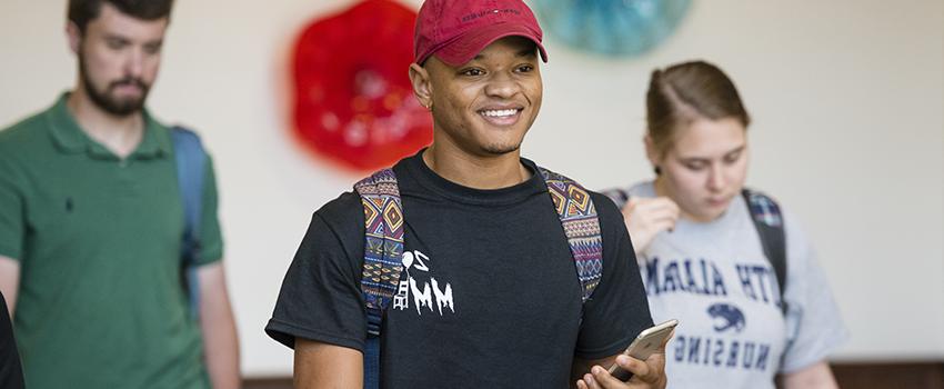 A male student smiling and walking out of a Nursing class